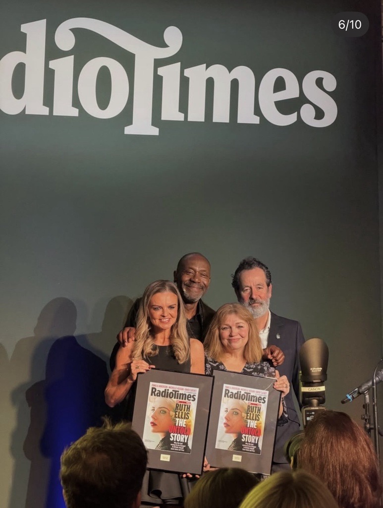 Laura Enston on stage with the Radio Times panel, holding a framed Ruth Ellis cover
